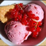 Eine Schüssel mit köstlichem Johannisbeereis, garniert mit frischen Johannisbeeren.