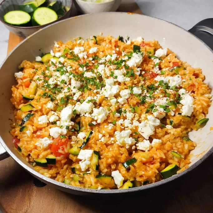 Zucchini-Reis-Pfanne mit Feta auf einem Teller angerichtet.