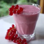 Roter Johannisbeer-Bananen-Smoothie in einem Glas mit frischen Zutaten