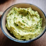 Zucchini-Avocado-Aufstrich in einer kleinen Schüssel auf einem Holztisch